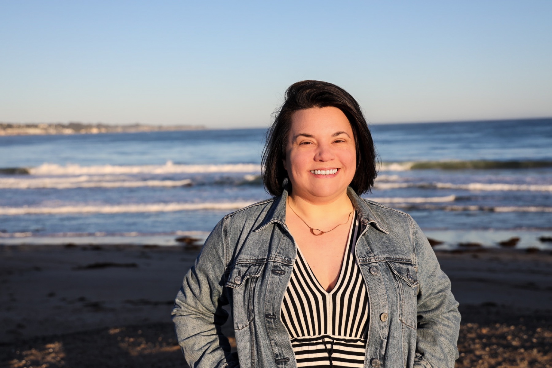 Dr. Victoria Verlezza standing on a beach at golden hour, smiling